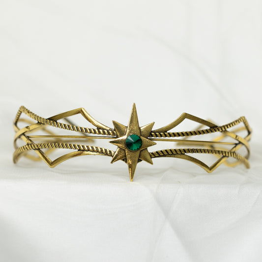 Gold bracelet with a green gemstone on a white background