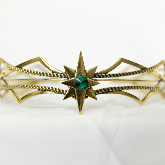 Gold bracelet with star design and green gemstone on a white background
