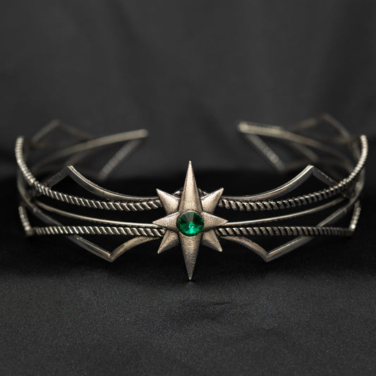Silver headpiece with a green gemstone on a black background