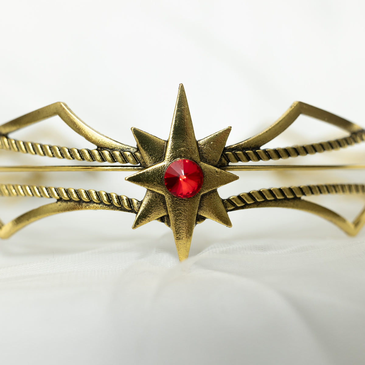 Gold headpiece with a red gemstone on a white background