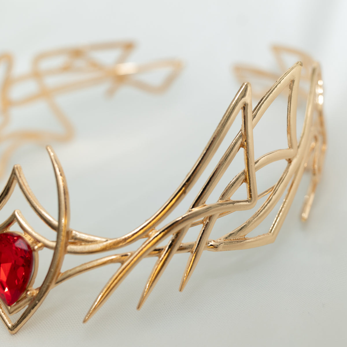 Gold bracelet with a red gemstone on a light background