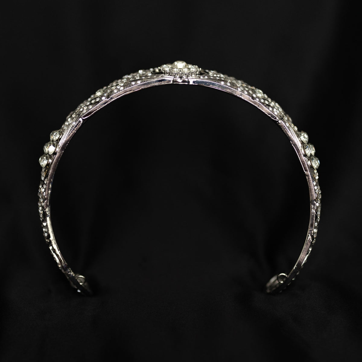 A silver-colored metal tiara with clear crystals set around the circumference, featuring a central decorative front - Bottom View 