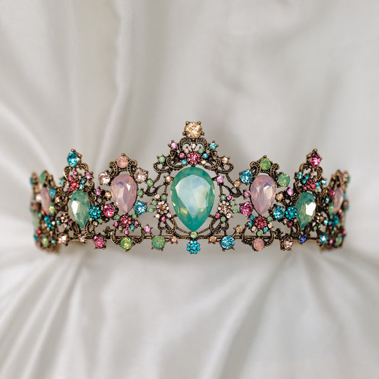 Tiara with multi color tear drop stones, light blue, light ping, teal, with small round stones throughout set in antique gold color metal - Front Close Up 