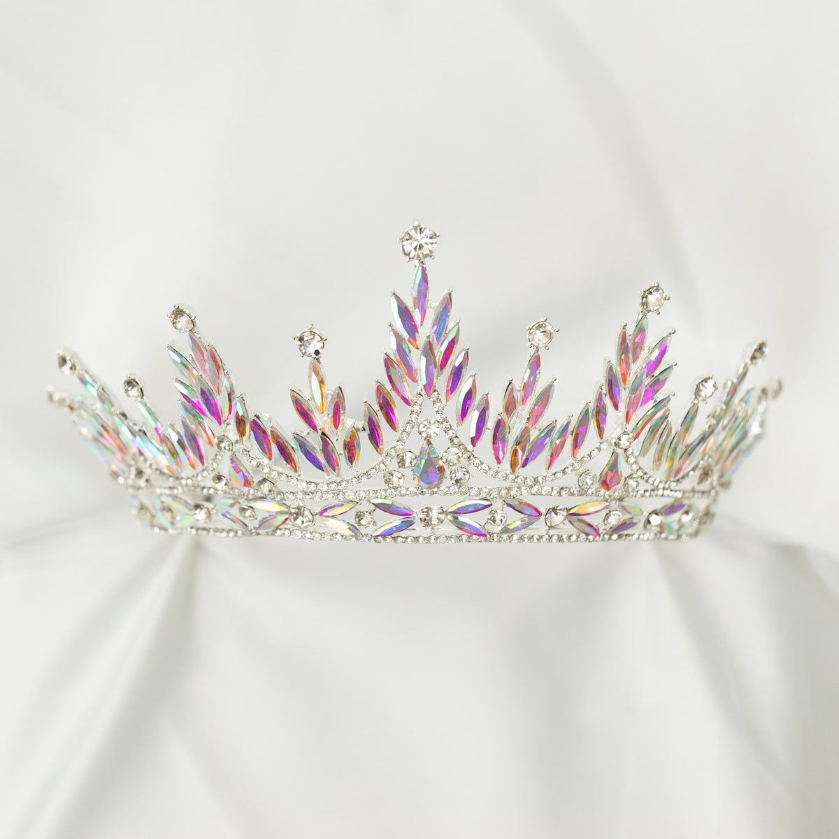 Sparkling tiara with multicolored gemstones on a light gray background