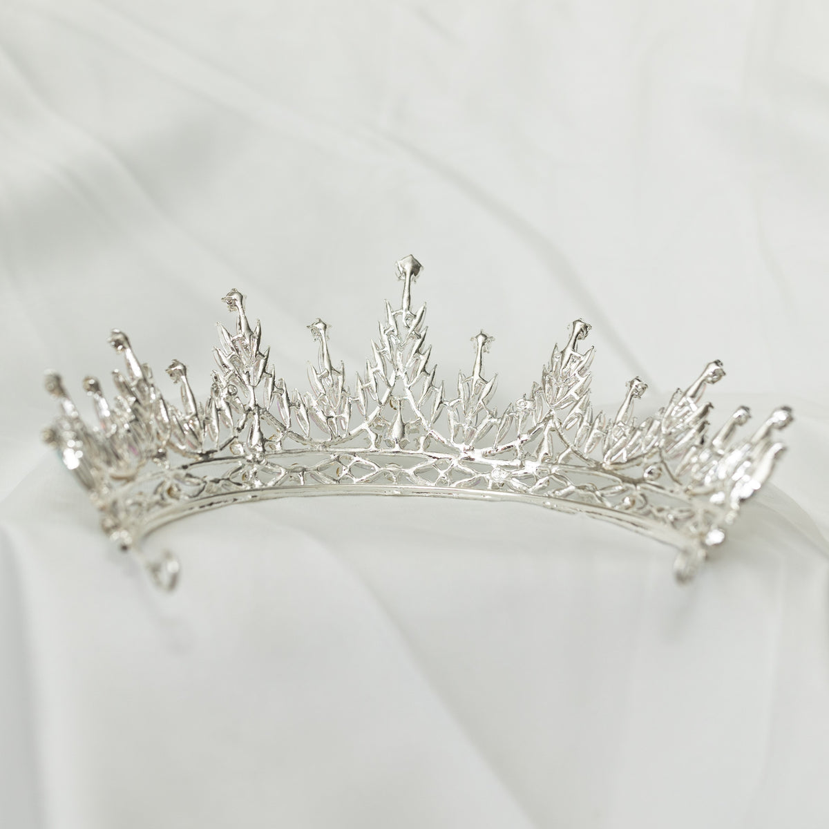 Silver tiara on a white fabric background