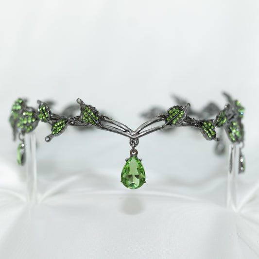 An elegant circlet crown featuring green drop jewels and leaf details, with an antique silver finish.