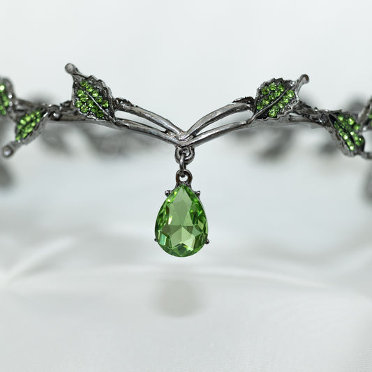 An elegant circlet crown featuring green drop jewels and leaf details, with an antique silver finish.