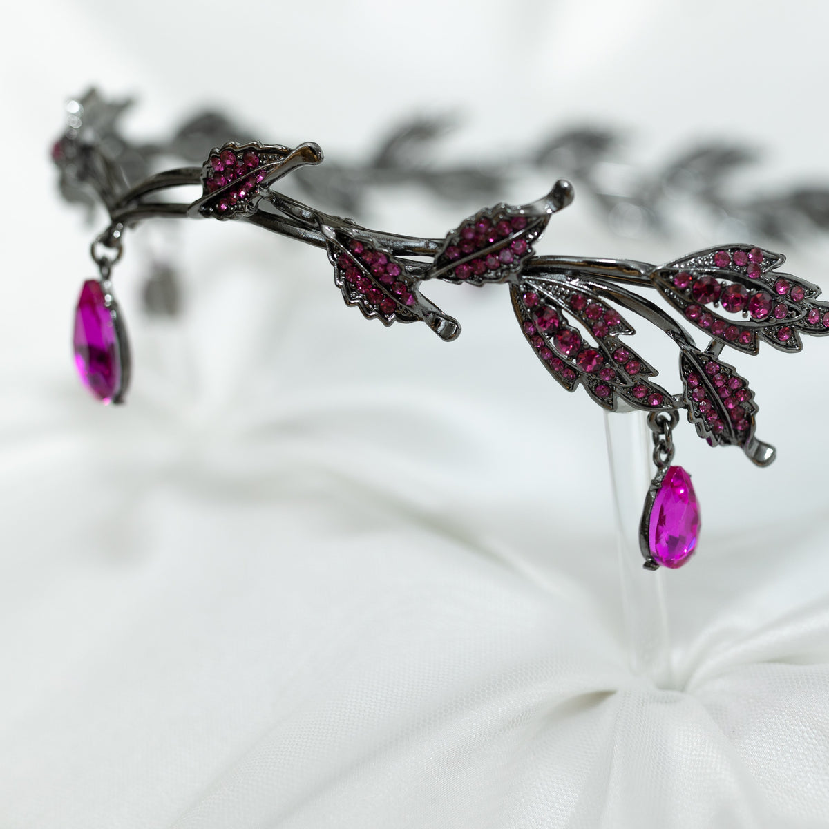 An elegant circlet featuring a hot pink crystal drop as the centerpiece, antique silver color metal with leaf-shaped embellishments and smaller pink crystals, set against a white background.