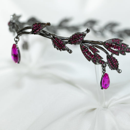 An elegant circlet featuring a hot pink crystal drop as the centerpiece, antique silver color metal with leaf-shaped embellishments and smaller pink crystals, set against a white background.