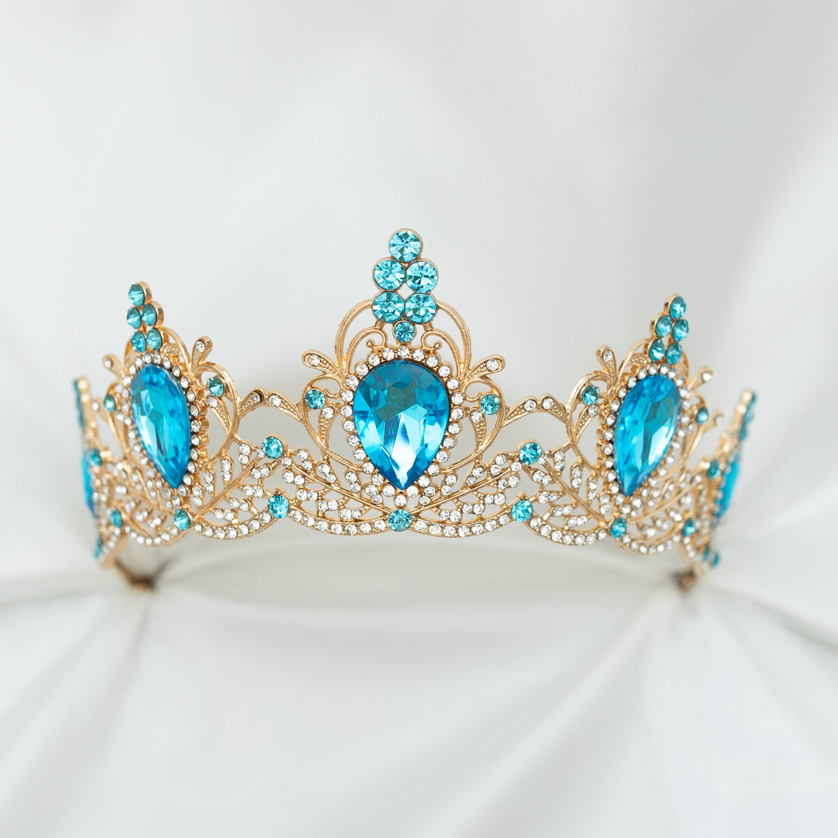 Gold tiara with blue gemstones on a white background