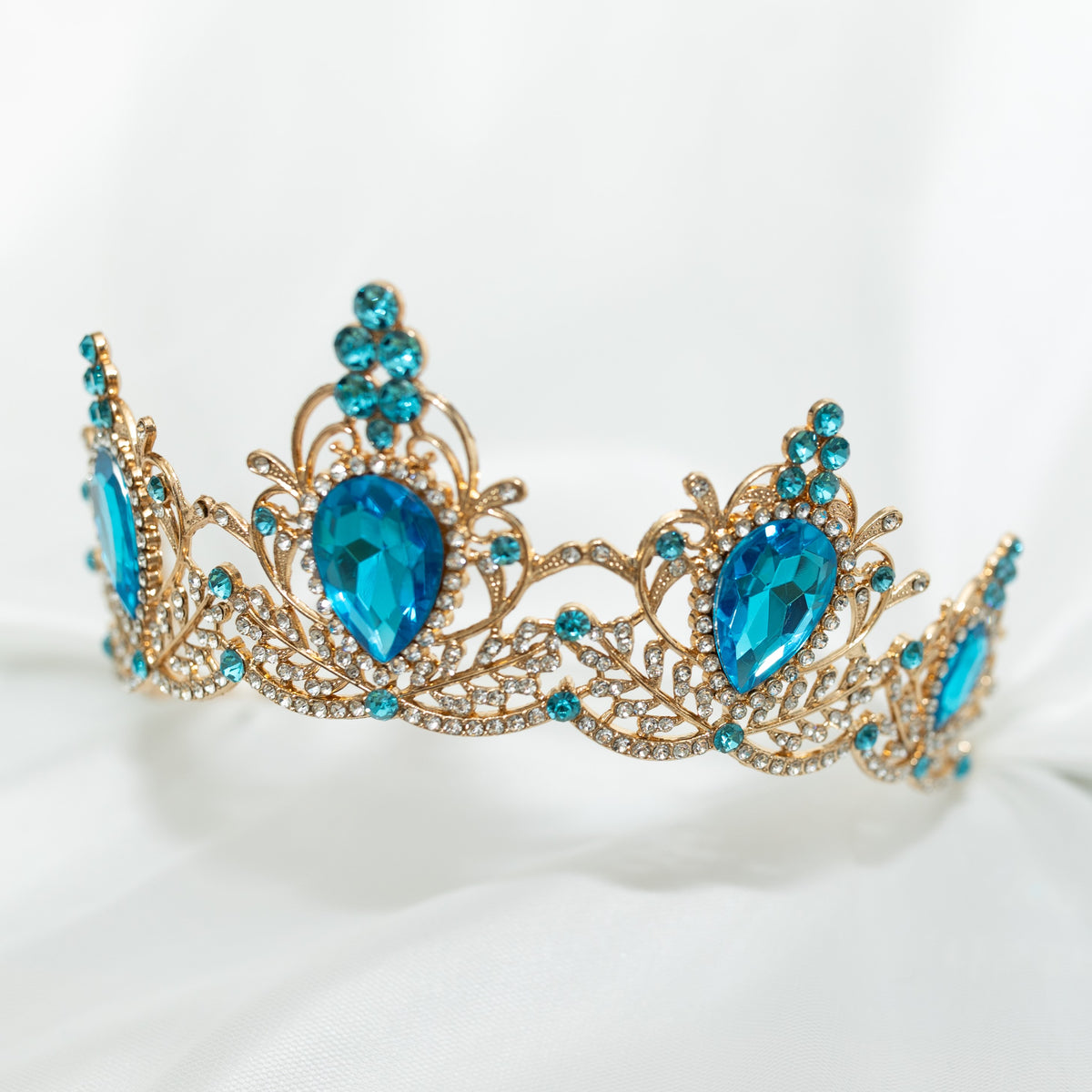 Gold tiara with blue gemstones on a white background