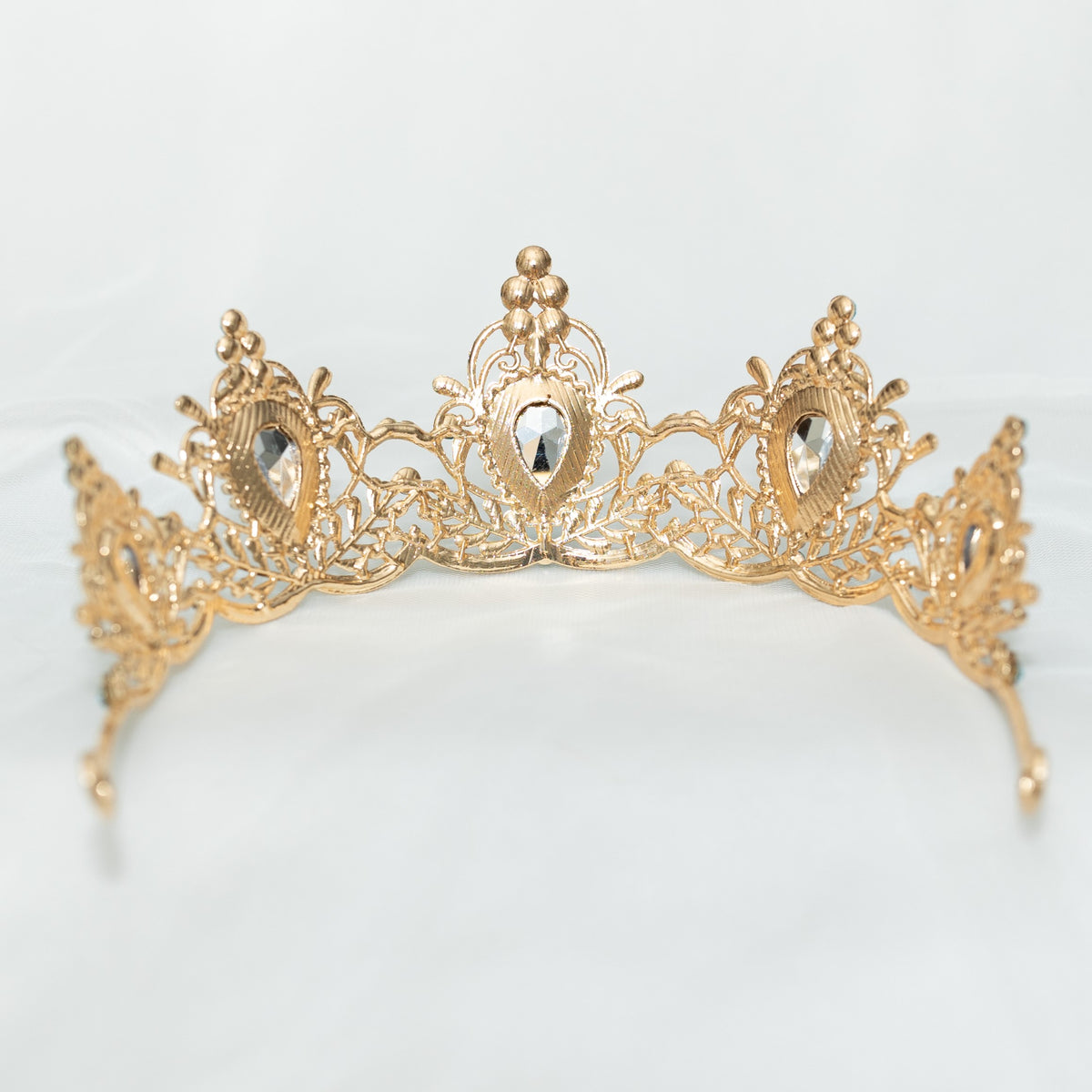 Gold tiara with intricate design on a light gray background