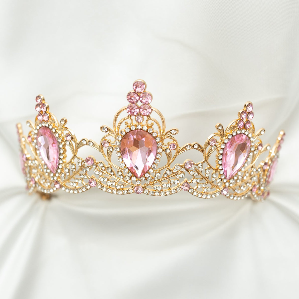 Gold tiara with pink gemstones on a white background