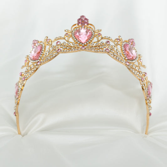 Gold tiara with pink gemstones on a white background