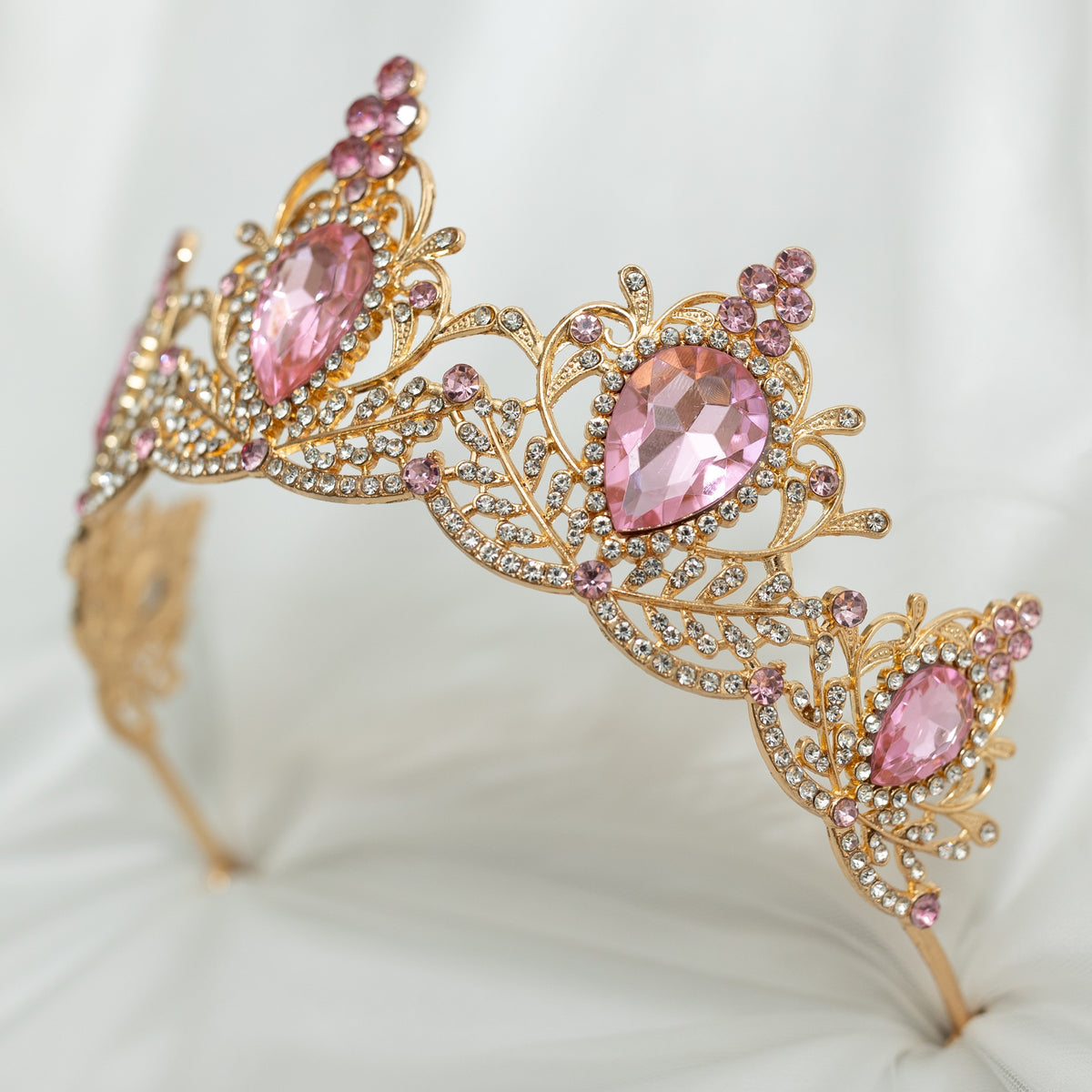 Gold tiara with pink gemstones on a white cushion