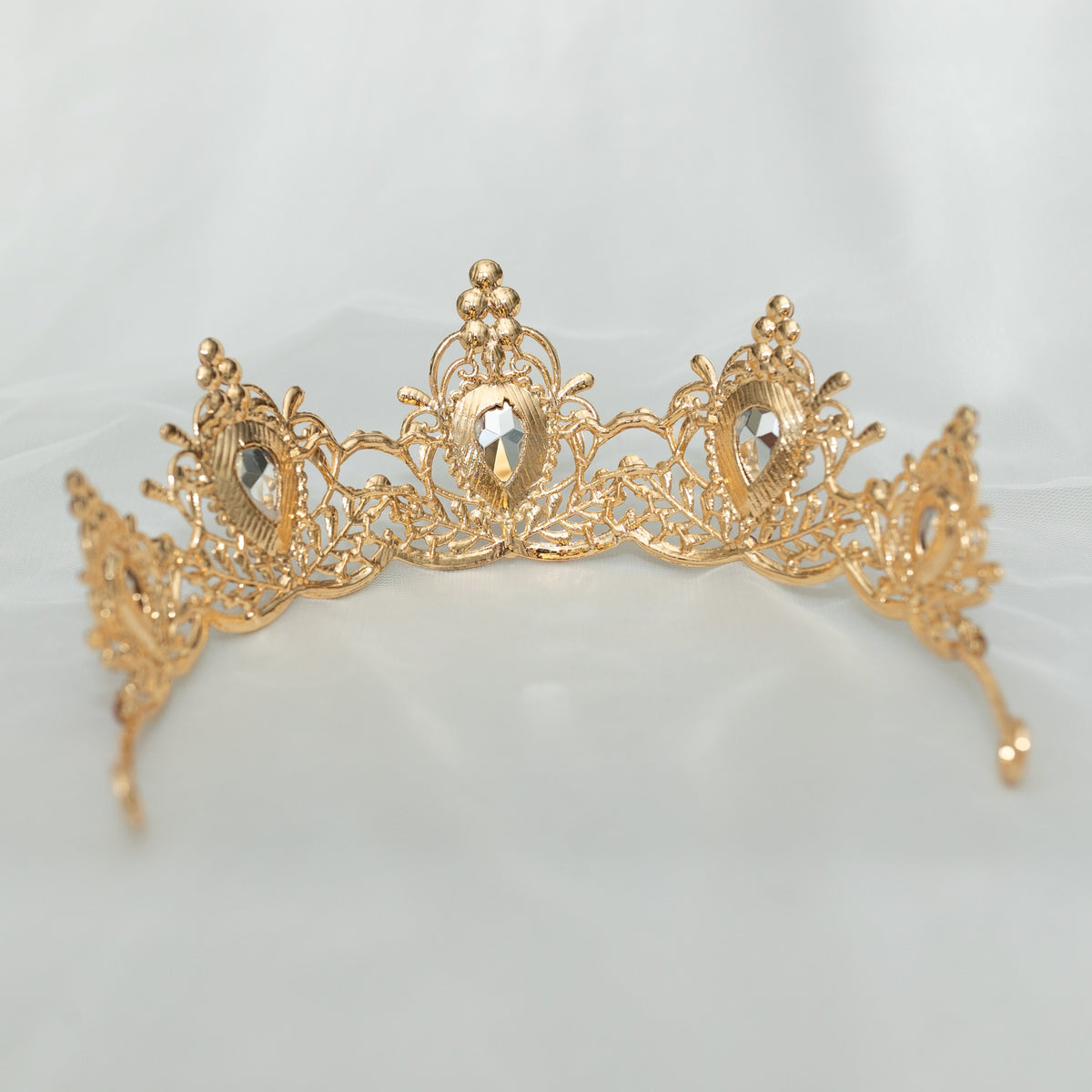 Gold tiara with pink gemstones on a light gray background - rear view 