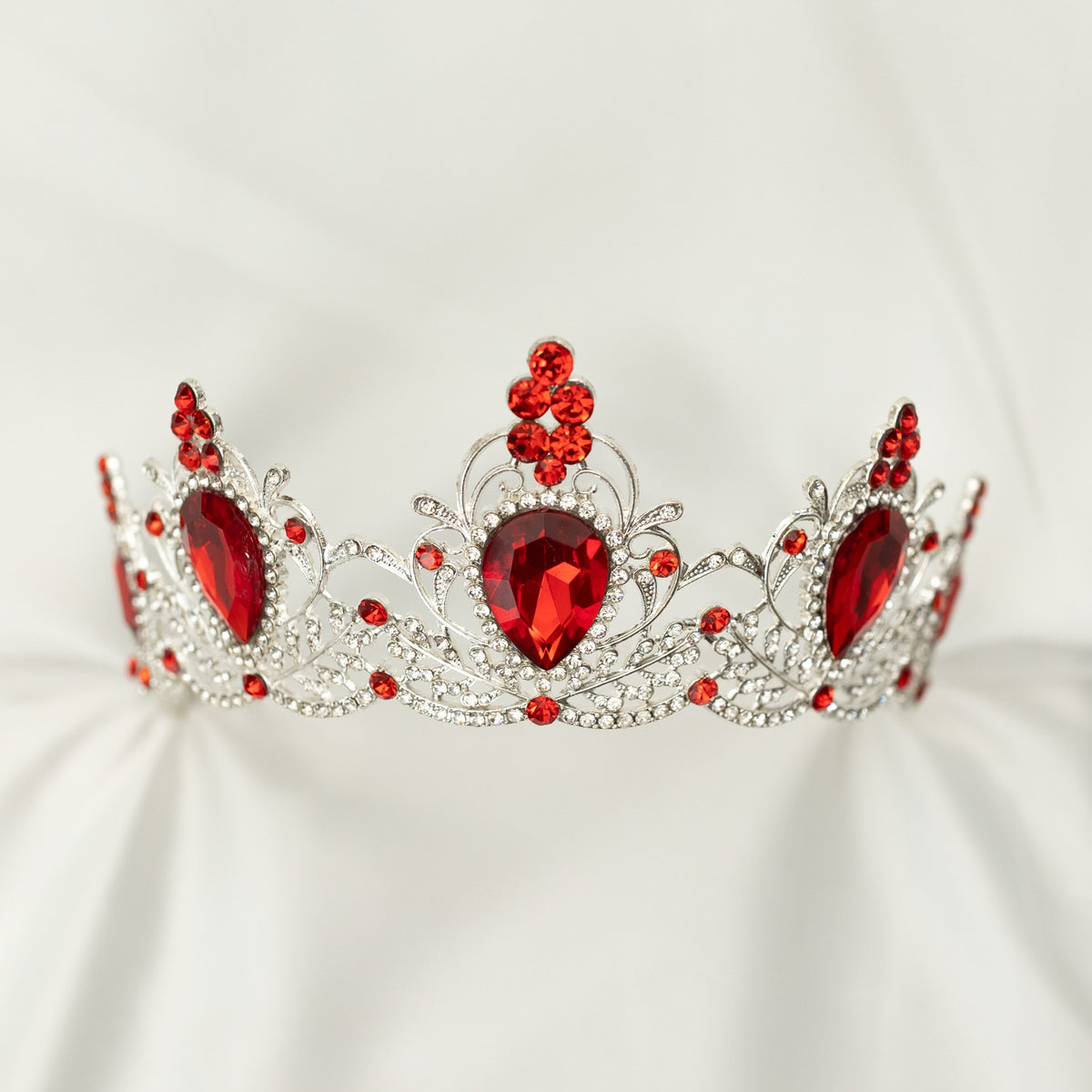 Silver tiara with red gemstones on a white background