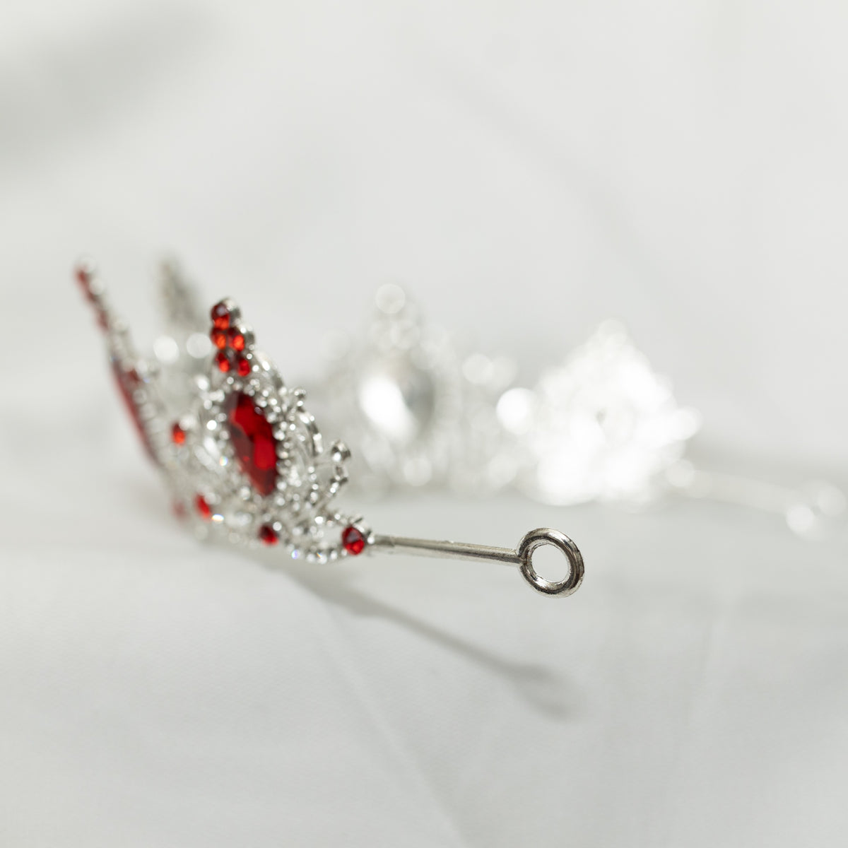 Silver earring with red gemstones on a light gray background