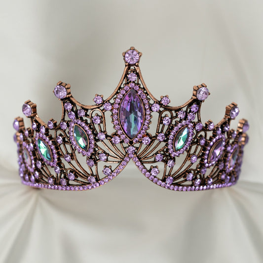 Decorative tiara with purple and green gemstones on a light background