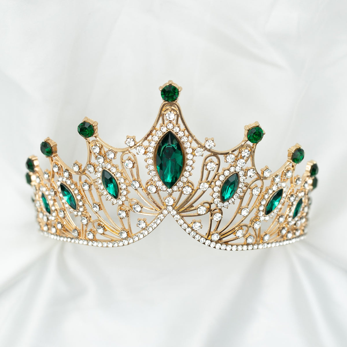 A golden tiara adorned with large green marquise shaped crystals and small clear round crystals, set against a white background. Front view 