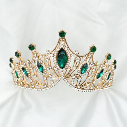 A golden tiara adorned with large green marquise shaped crystals and small clear round crystals, set against a white background. Front view 