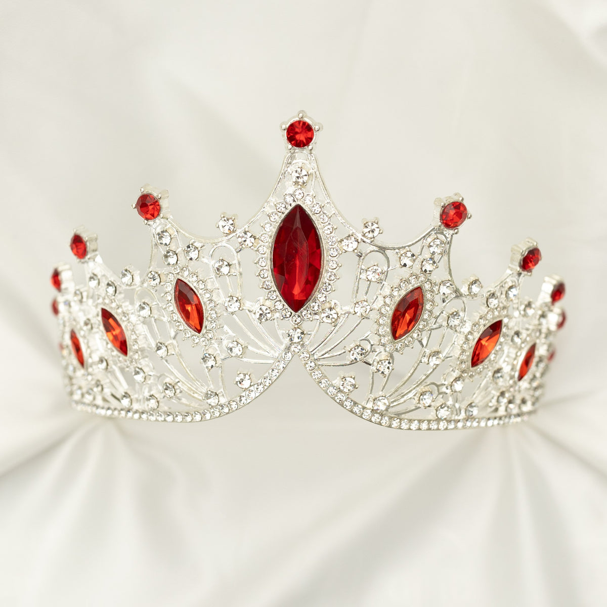 Silver tiara with red gemstones on a white background