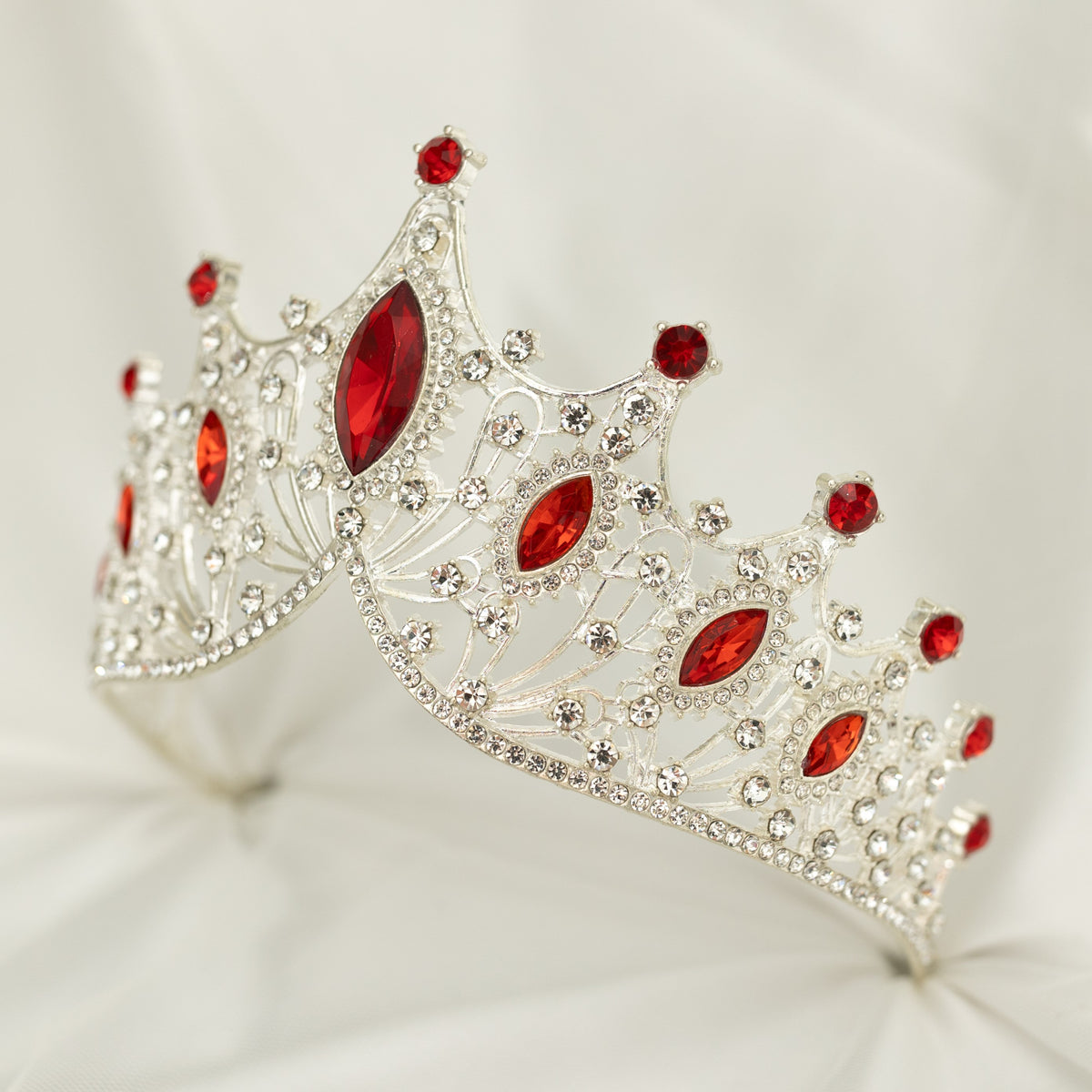 Silver tiara with red gemstones on a white background