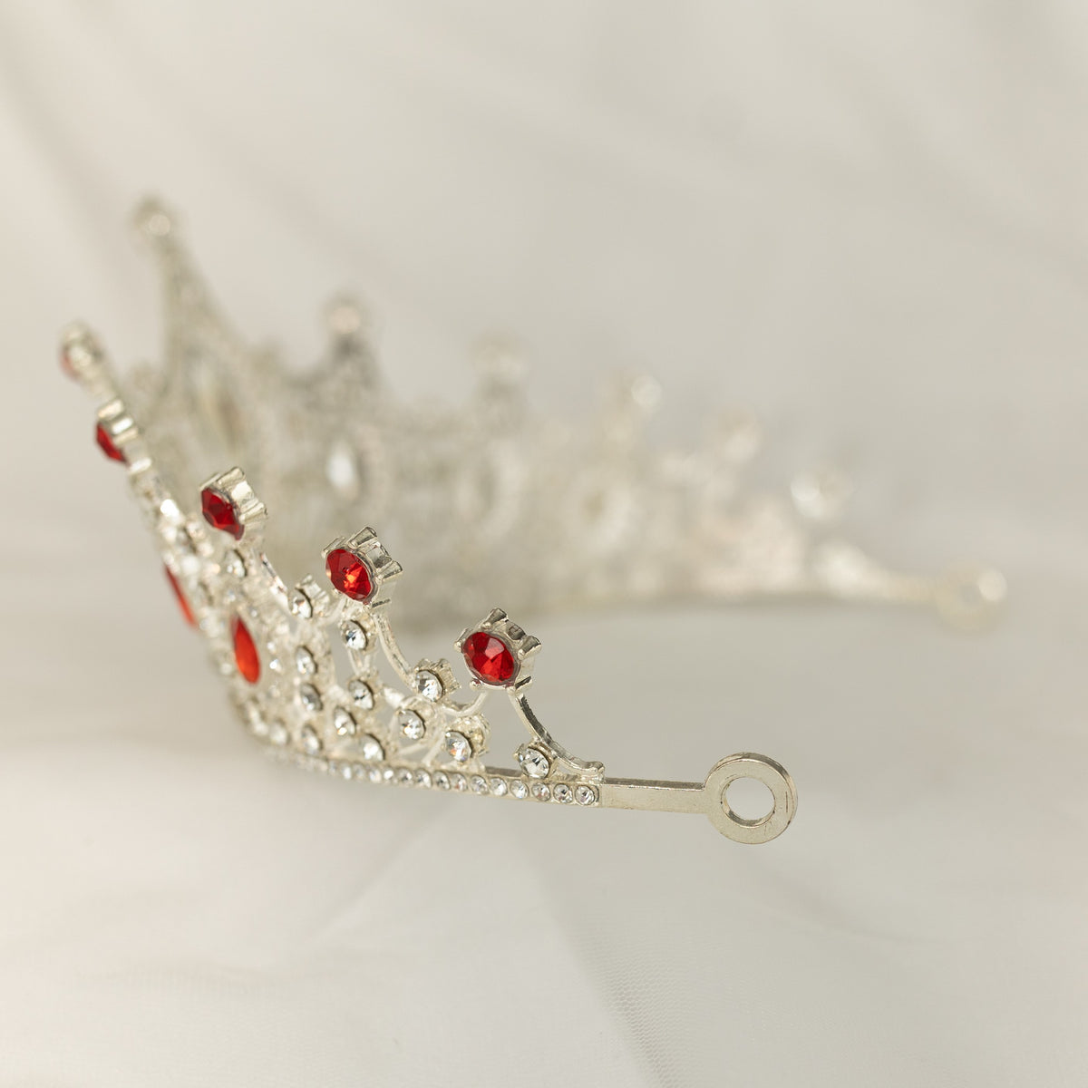 Silver tiara with red gemstones on a light background