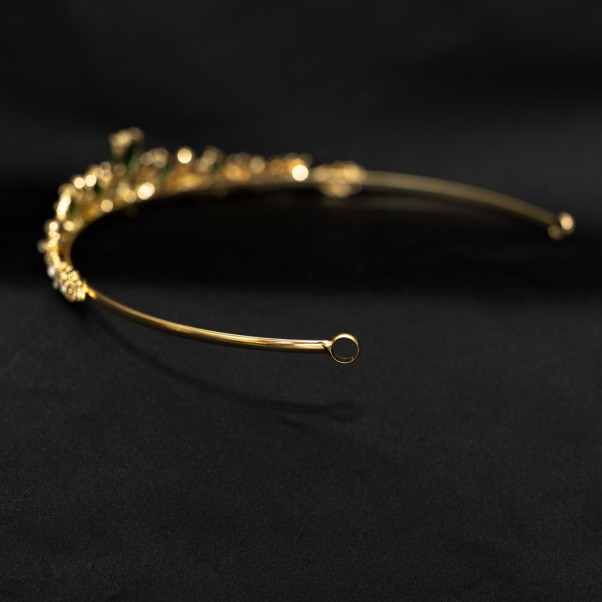 Gold headband with green gemstones on a black background