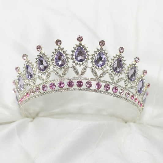 Elegant tiara with purple and pink gemstones on a white cushion