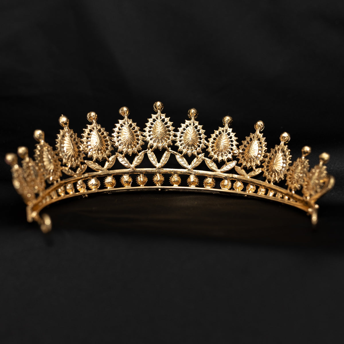 Gold tiara with intricate design on a black background