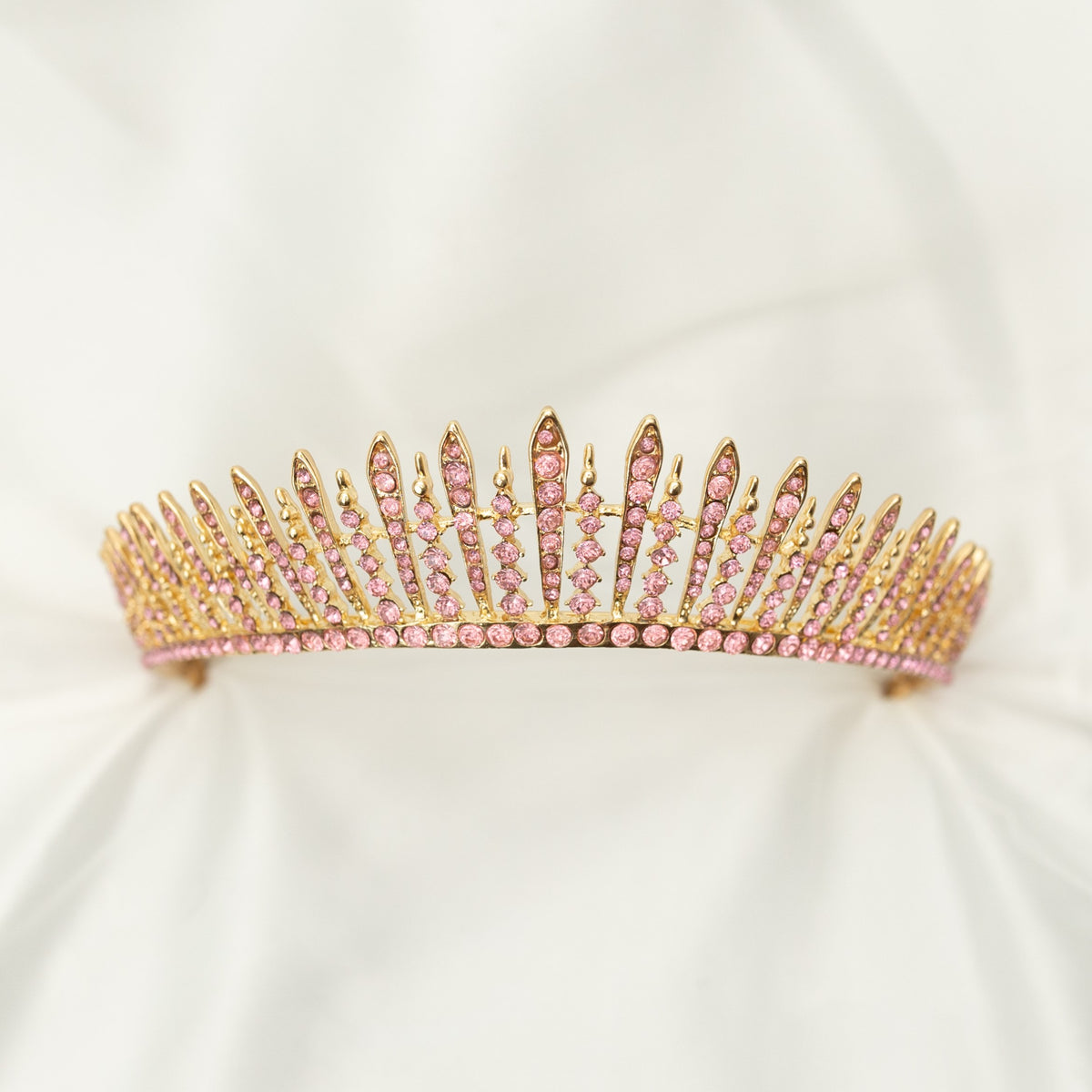 A pink and gold tiara with a spire design, featuring clear crystals. Front view