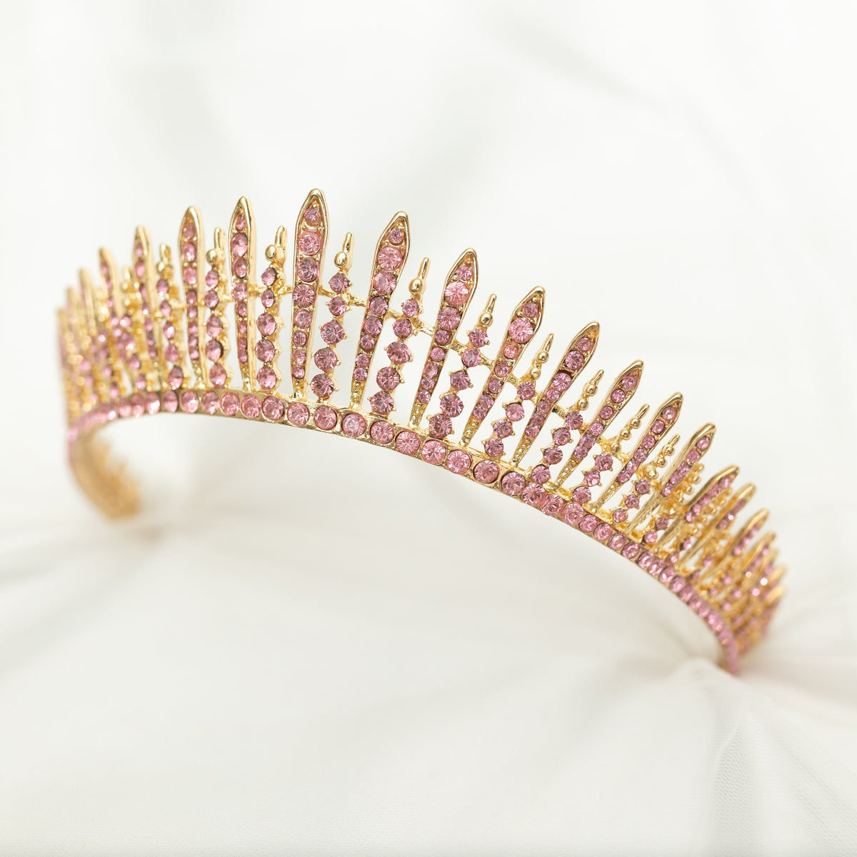 A pink and gold tiara with a spire design, featuring clear crystals. Side front view 