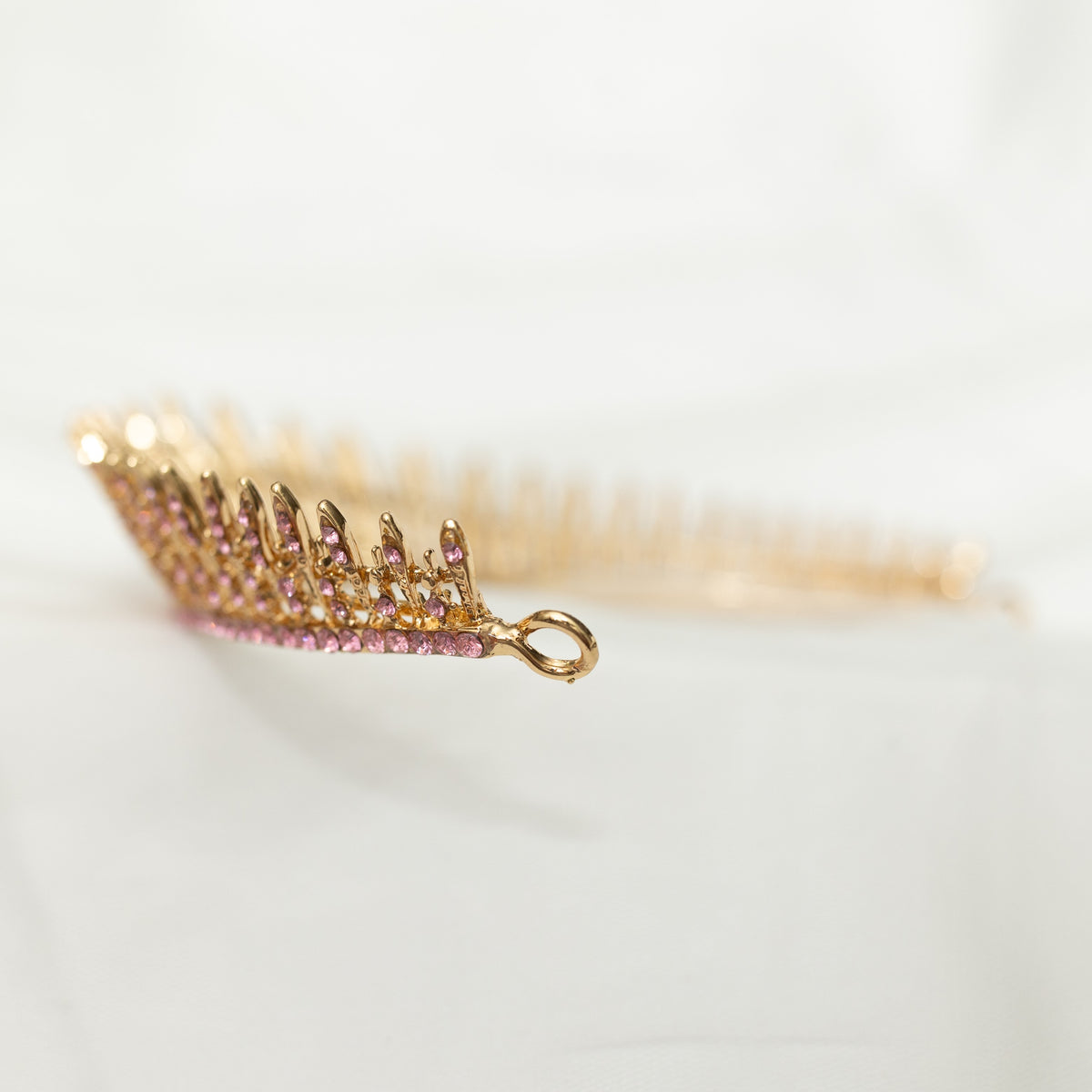 A pink and gold tiara with a spire design, featuring clear crystals.  End view 