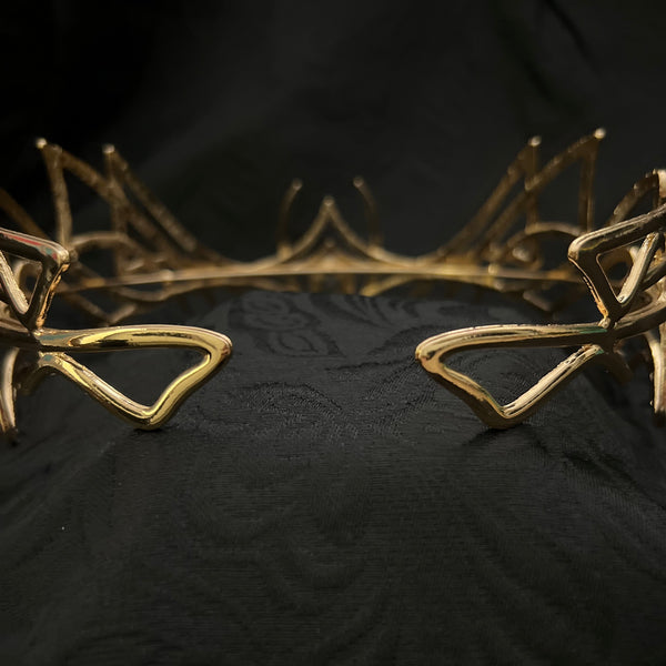 Close-up of a black textured garment with metallic gold abstract branch-like trim along the edge.