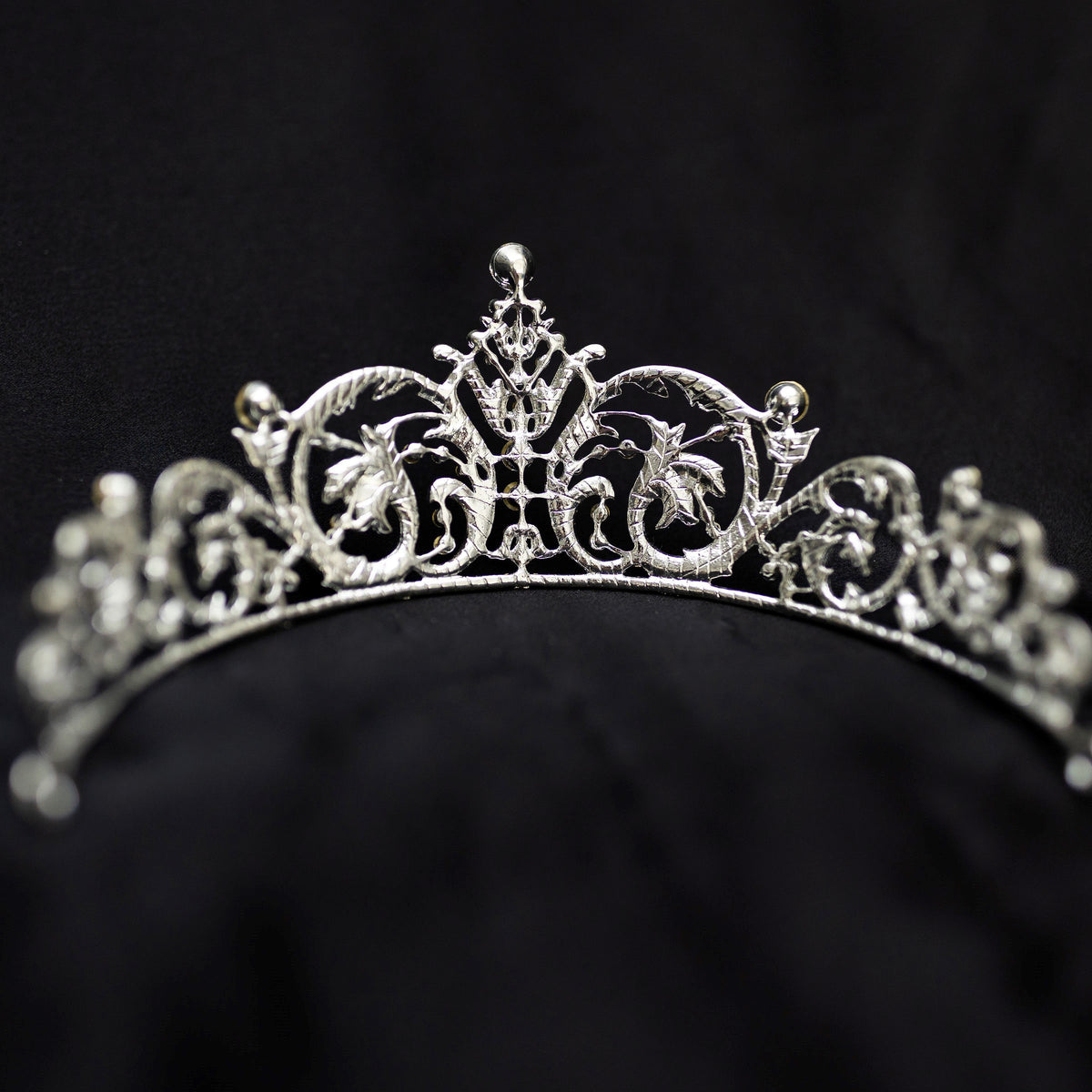 Elegant silver crystal tiara with intricate scrollwork design and sparkling rhinestones, photographed on a black background - Back View 