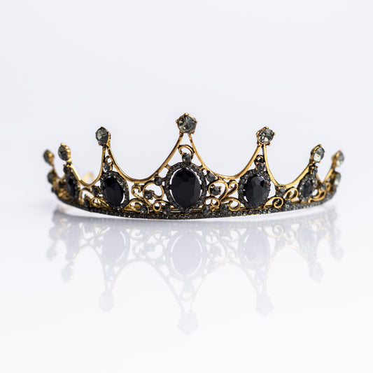A baroque-style tiara with black colored crystals set in a yellow gold color setting, with loops on each end for securing to hair - Front